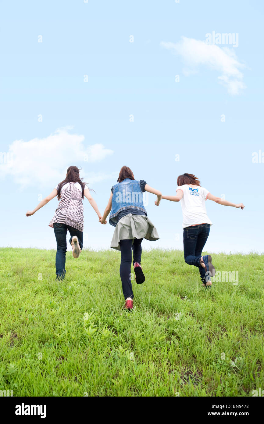 Three Young Women Holding Hands in Green Field Stock Photo - Alamy