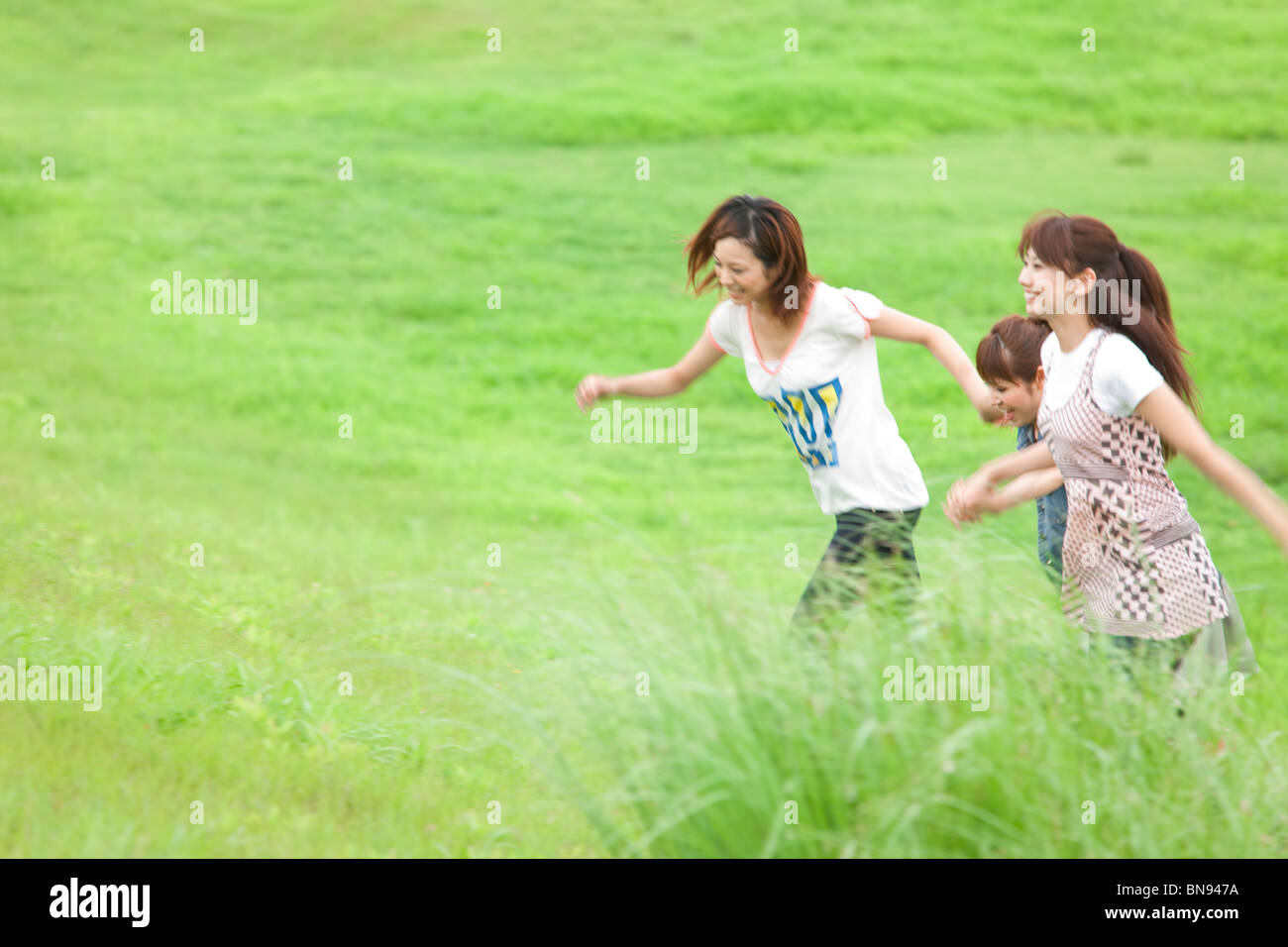 Three Young Women Holding Hands in Green Field Stock Photo - Alamy