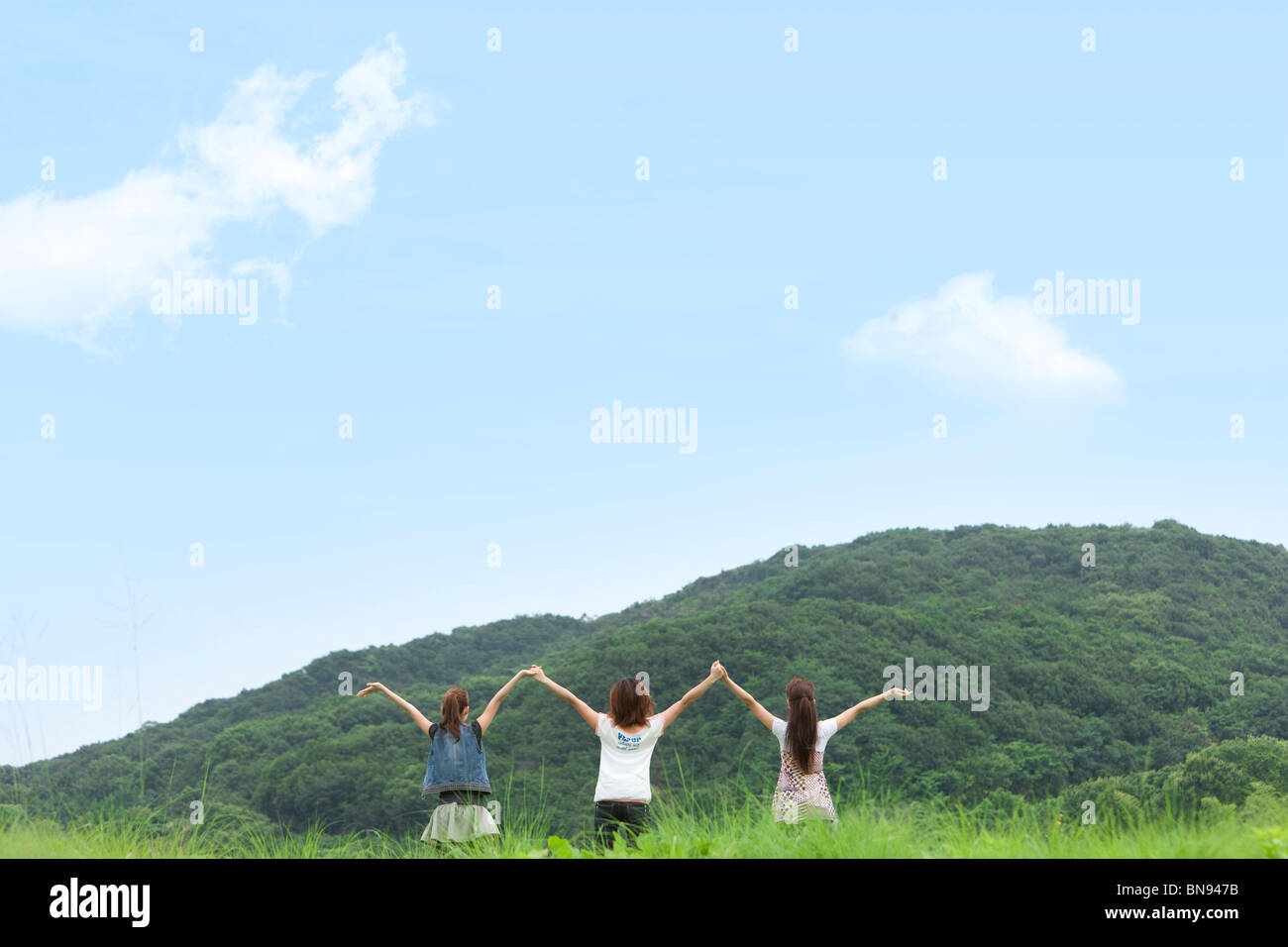 Three Young Women Holding Hands Up Together Stock Photo - Alamy