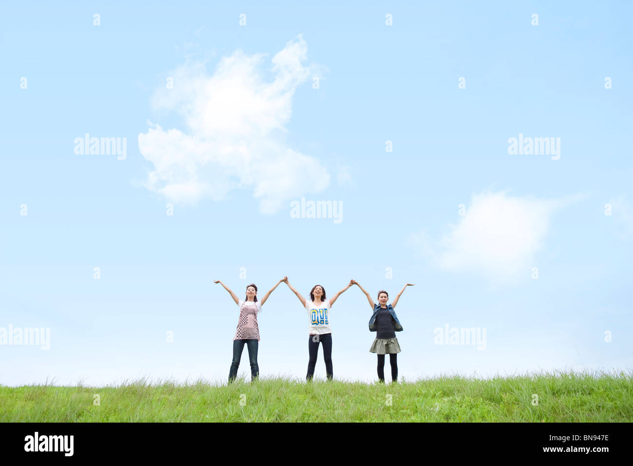 Three Young Women Holding Hands Up Together Stock Photo - Alamy