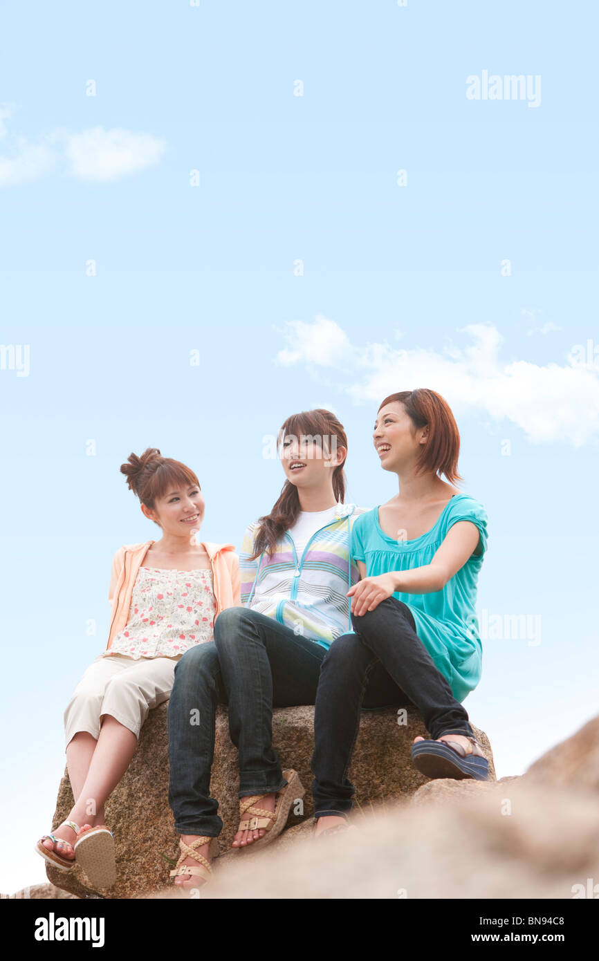 Three people sitting on rocks hi-res stock photography and images - Alamy