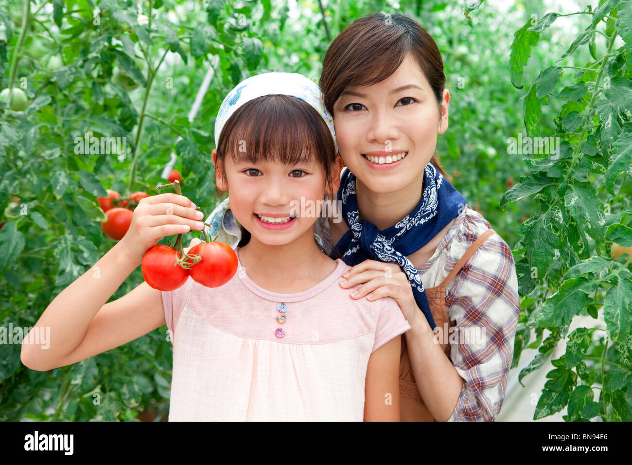 Portrait of girl with mother holding tomatoes smiling Stock Photo - Alamy