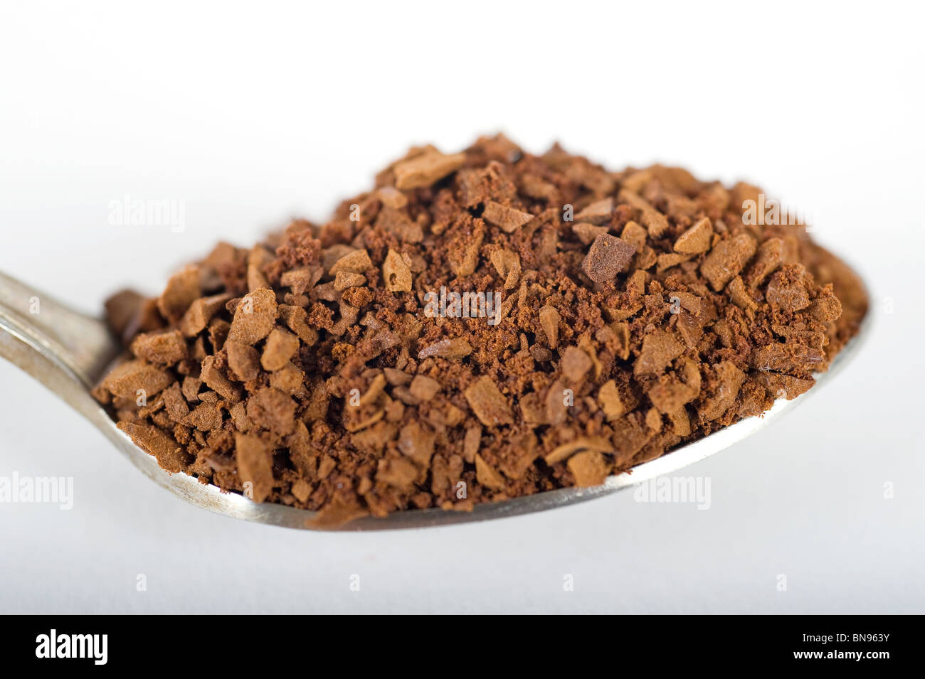 Teaspoon full of instant coffee granules isolated on white Stock Photo