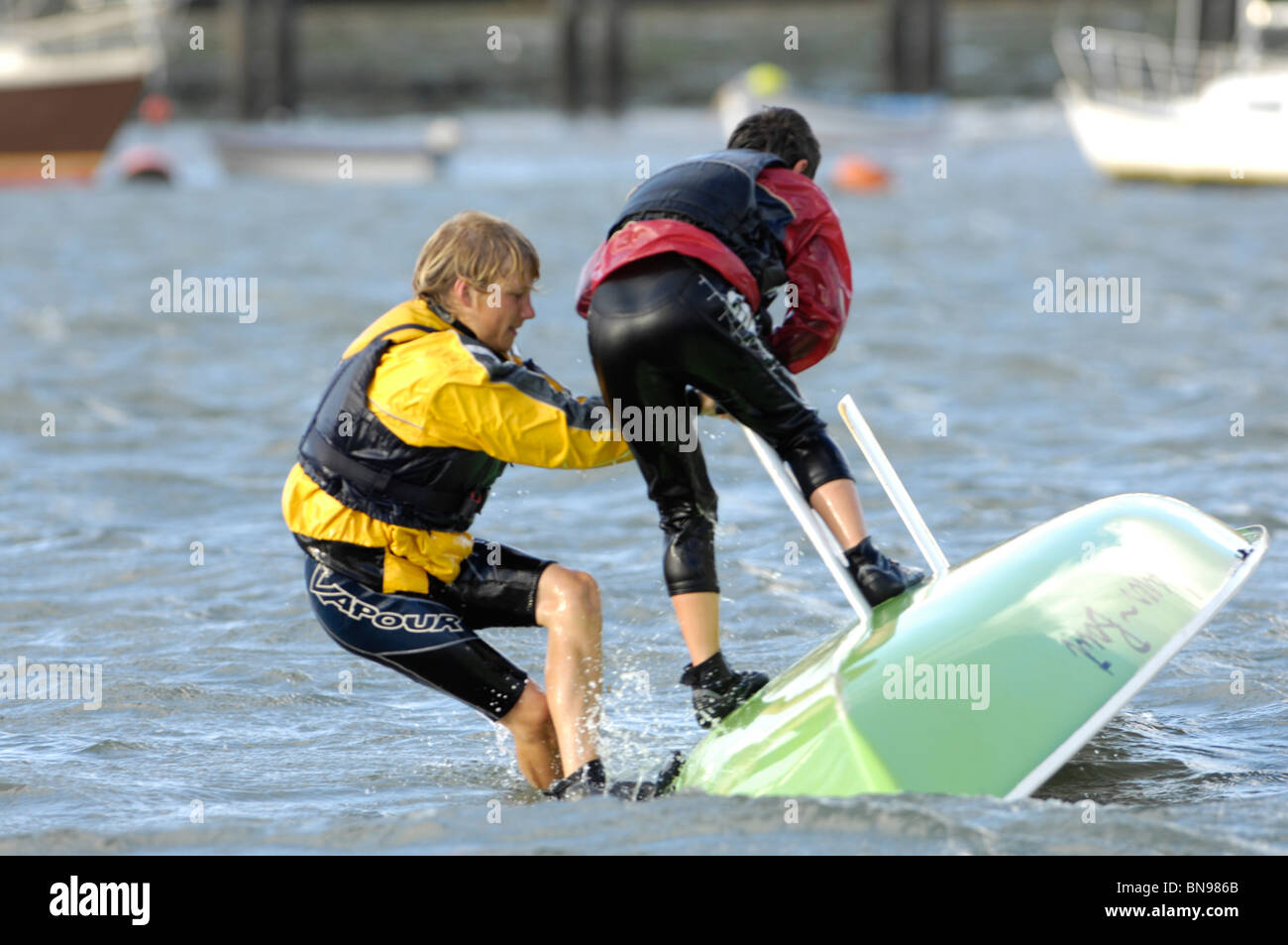 Two young boys righting a Laser yacht after capsizing in 18 knots of breeze on the River Hamble. United Kingdom. Stock Photo