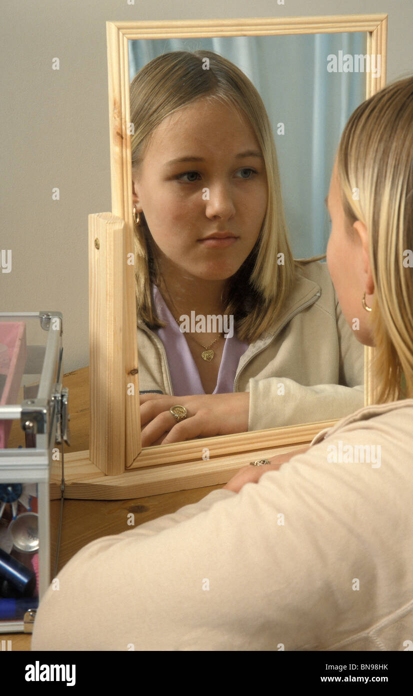 Unhappy teenage girl looking in mirror Stock Photo