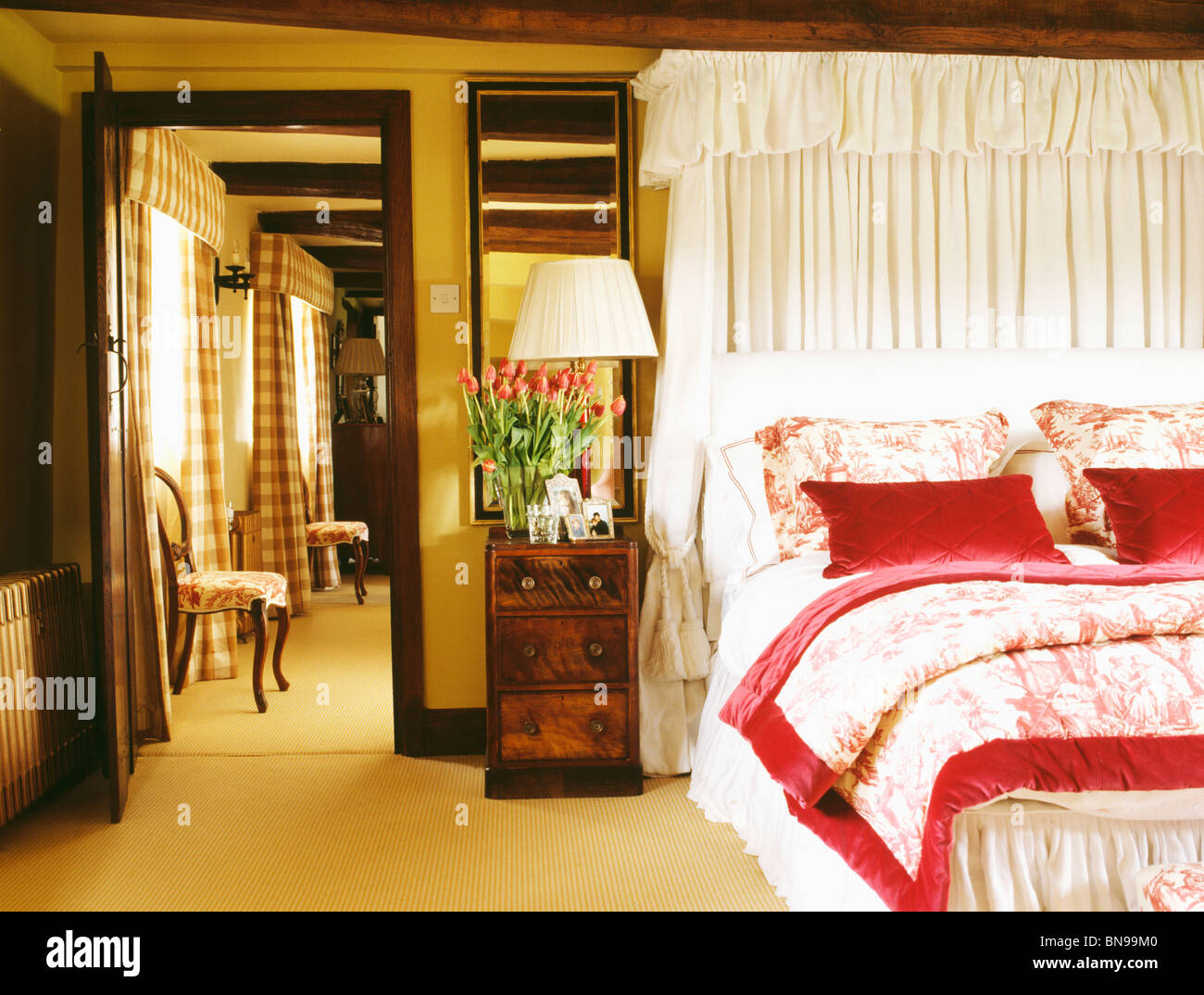 White Drapes Above Bed With Toile De Jouy Bedlinen And Red Silk