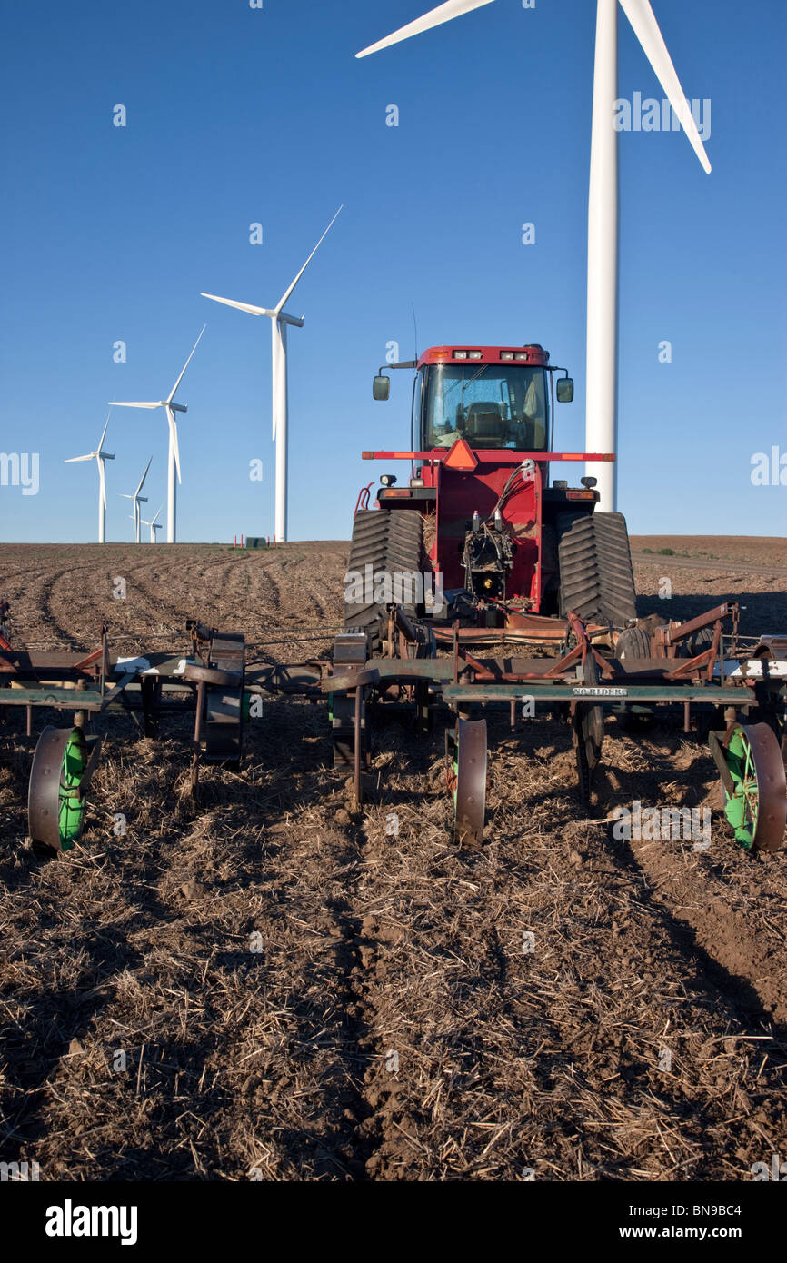 Tractor dragging harrow, fallow wheat field, wind farm Stock Photo