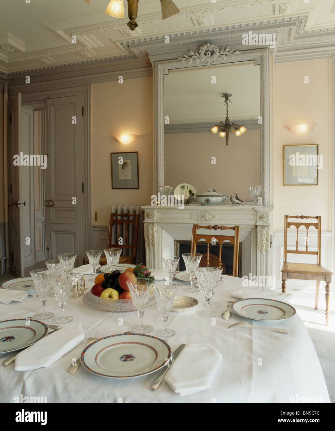 Place settings on table with white cloth in dining room with antique