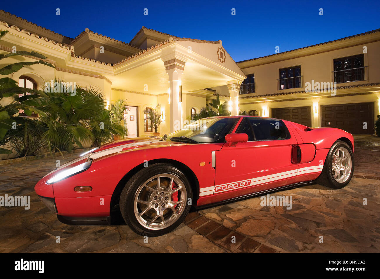 Red Ford GT sports-car in front of Spanish villa lit at night Stock Photo