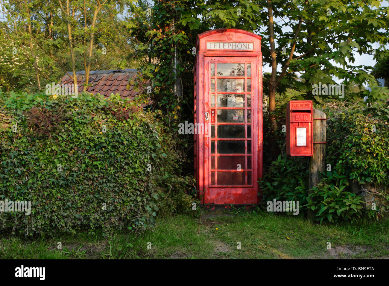 A neglected looking traditional English red telephone box and well ...