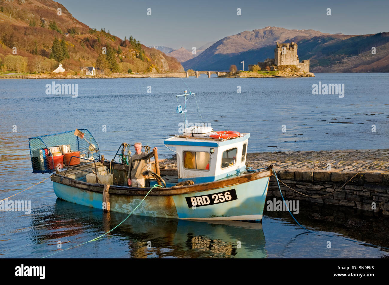 Local Fisherman in Fishing Boat, & Eilean Donan Castle, Loch Duich, Scottish Highlands, Scotland, UK Stock Photo