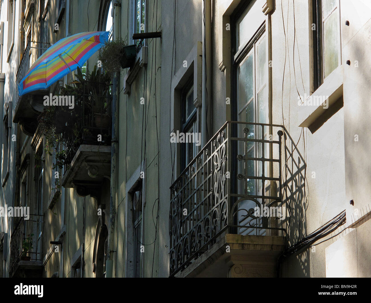 A view of balconies upon a Lisbon Building in Portugal with a brightly coloured Umbrella providing shade Stock Photo