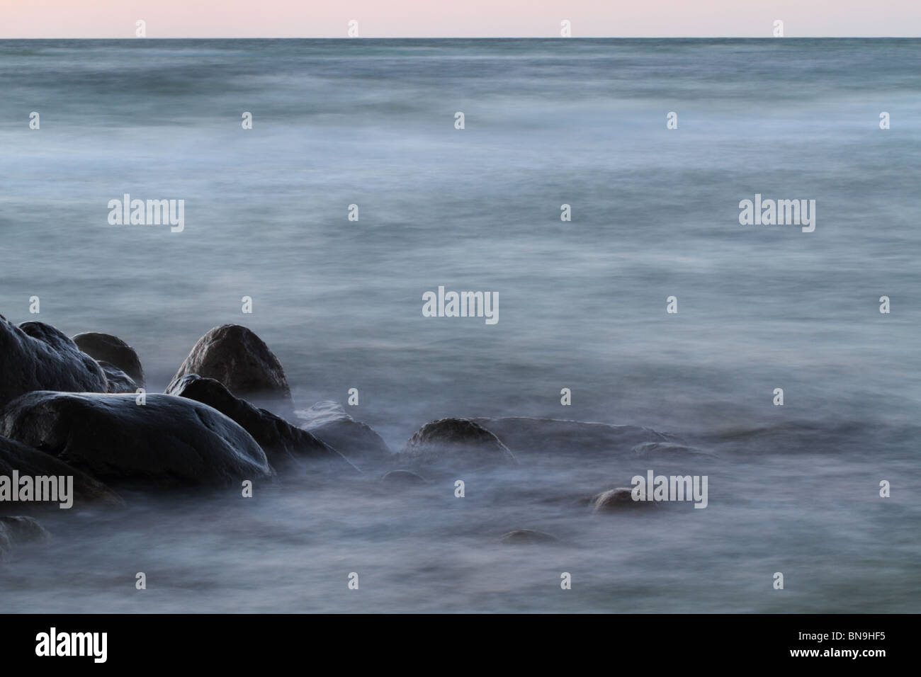 Waves breaking on rocks in the evening Stock Photo