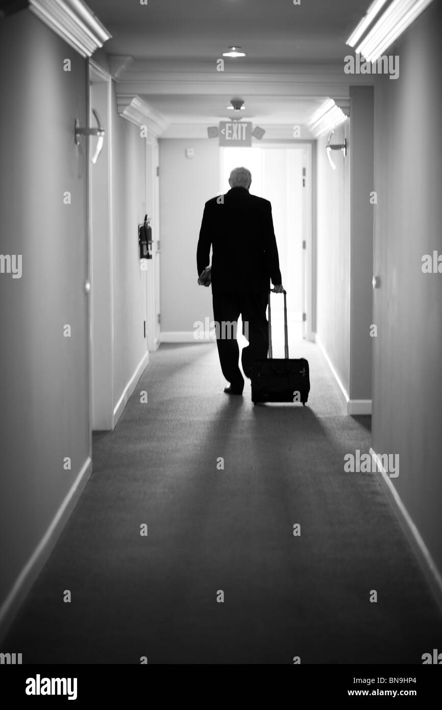 Caucasian businessman pulling luggage in hotel hallway Stock Photo