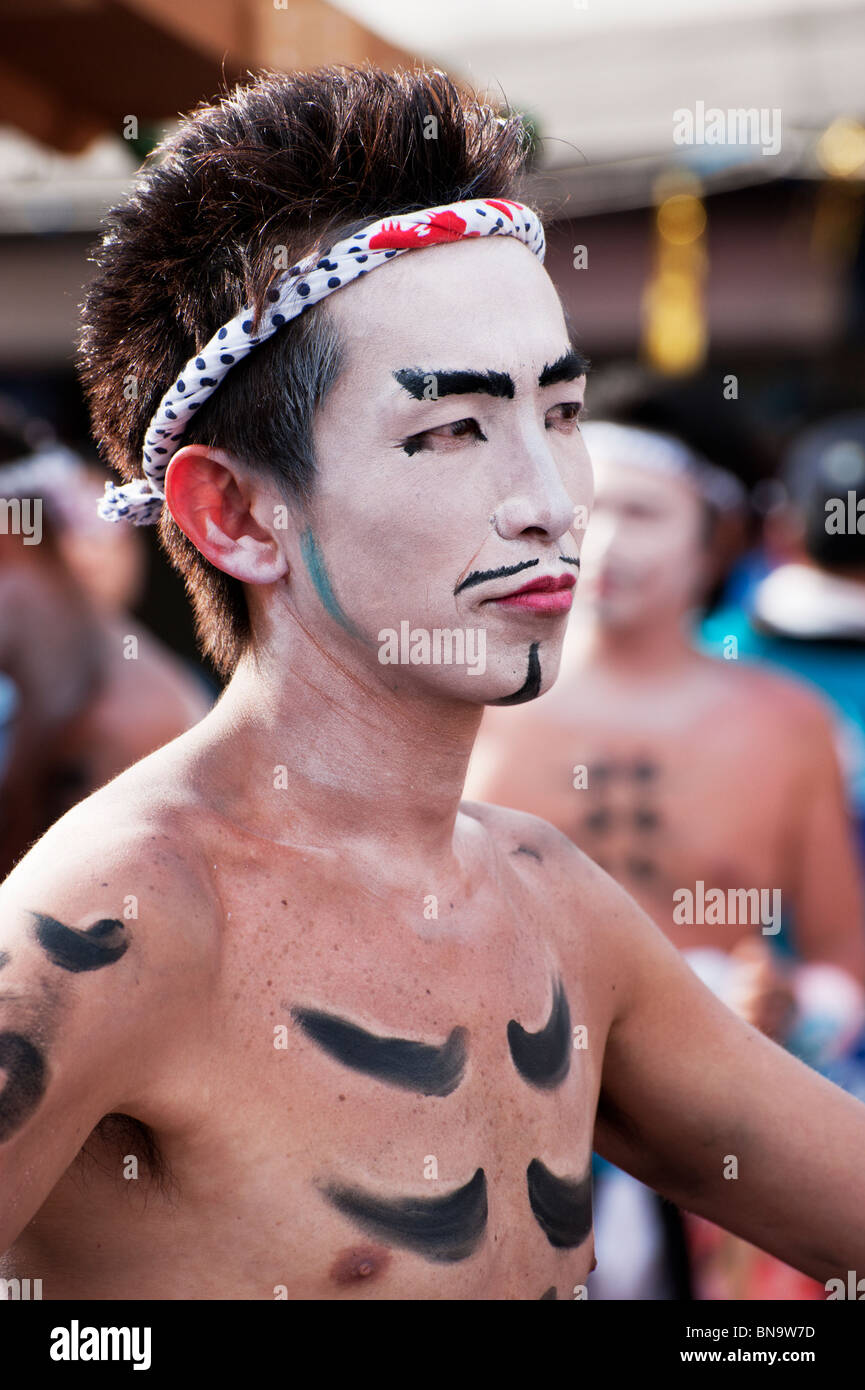 A Japanese man sports white face paint and a traditional headband during the Nagamochi dancing at the Onbashira Festival. Stock Photo