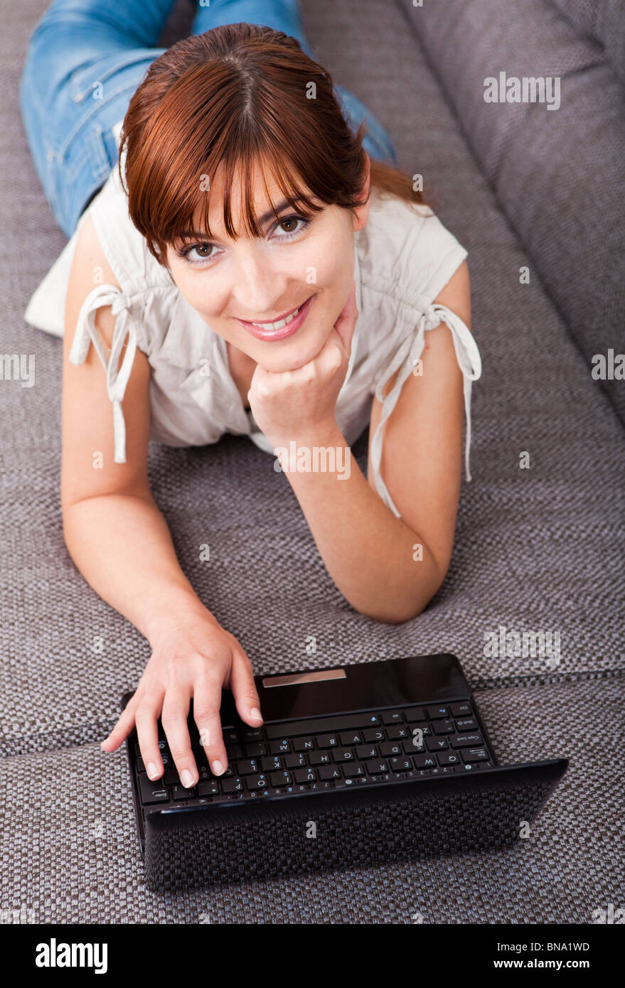 Beautiful woman at home lying on sofa and working with a laptop Stock ...