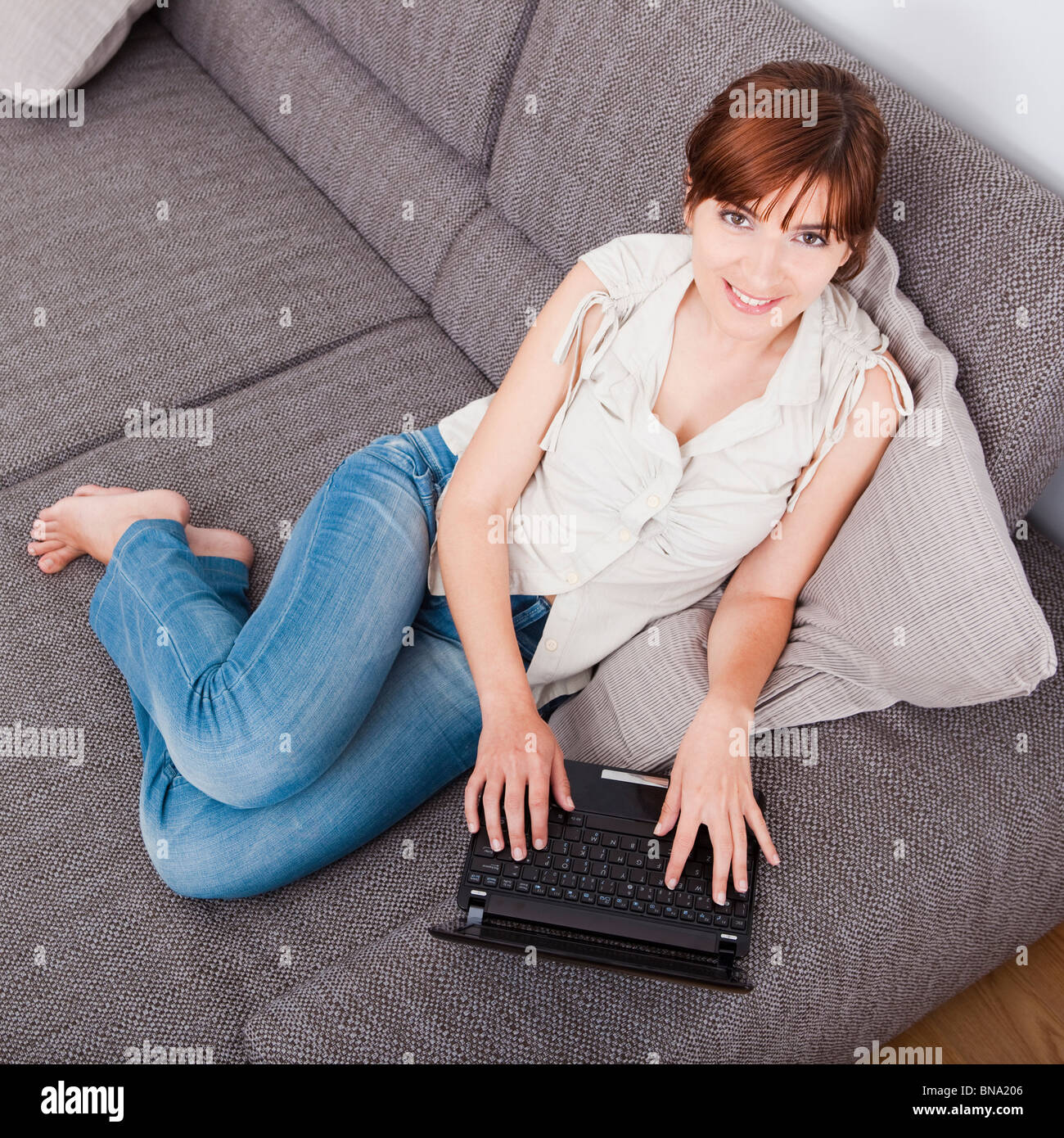 Beautiful woman at seated on sofa and working with a laptop Stock Photo ...