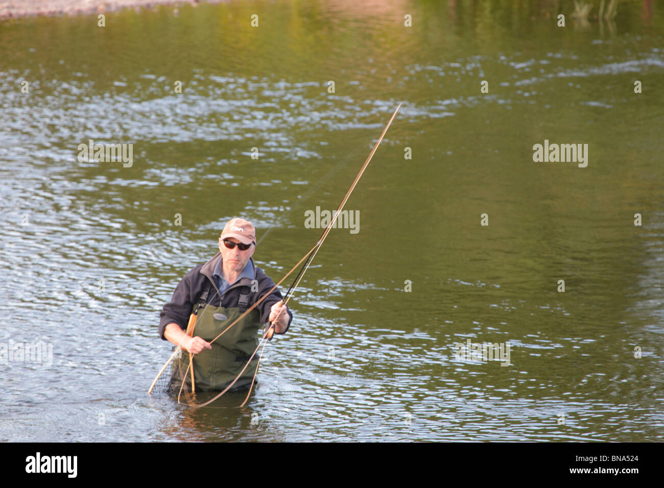Fly Fisherman wading in the River Eden fishing for Sea Trout near Carlisle, Cumbria, England, United Kingdom. Stock Photo
