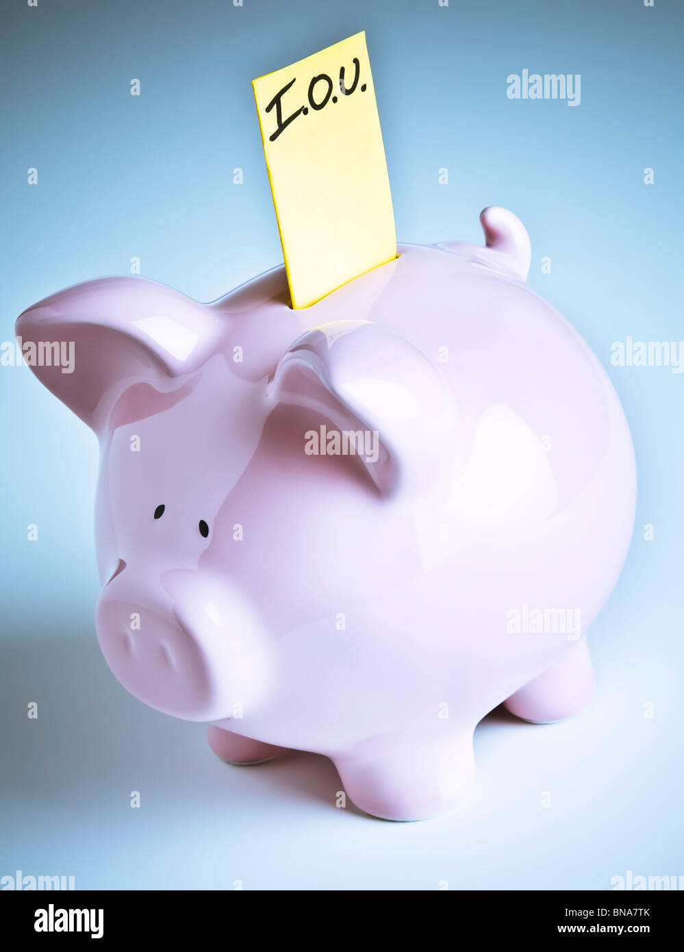 Piggy bank with IOU sticking out of its coin slot. Stock Photo