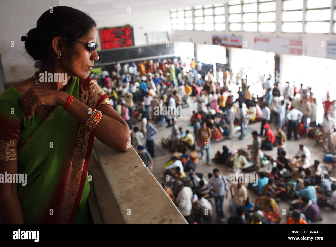 A women watches crowded ticket hall at New Delhi Railway Station in Delhi, India. Stock Photo