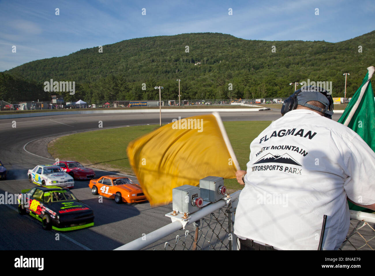 Woodstock, New Hampshire - The flagman waves signal flags during stock car racing at White Mountain Motorsports Park. Stock Photo