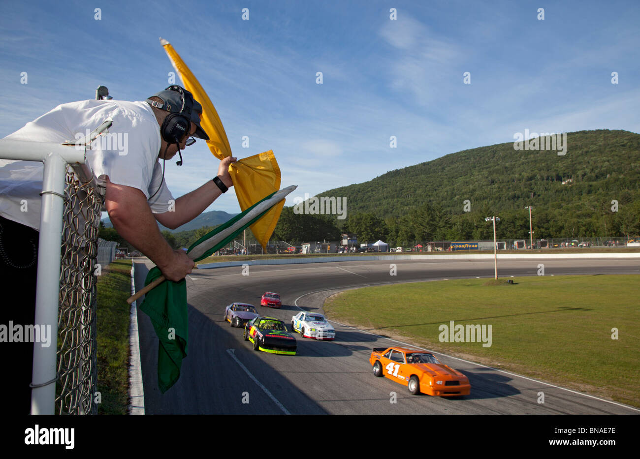 Woodstock, New Hampshire - The flagman waves signal flags during stock car racing at White Mountain Motorsports Park. Stock Photo