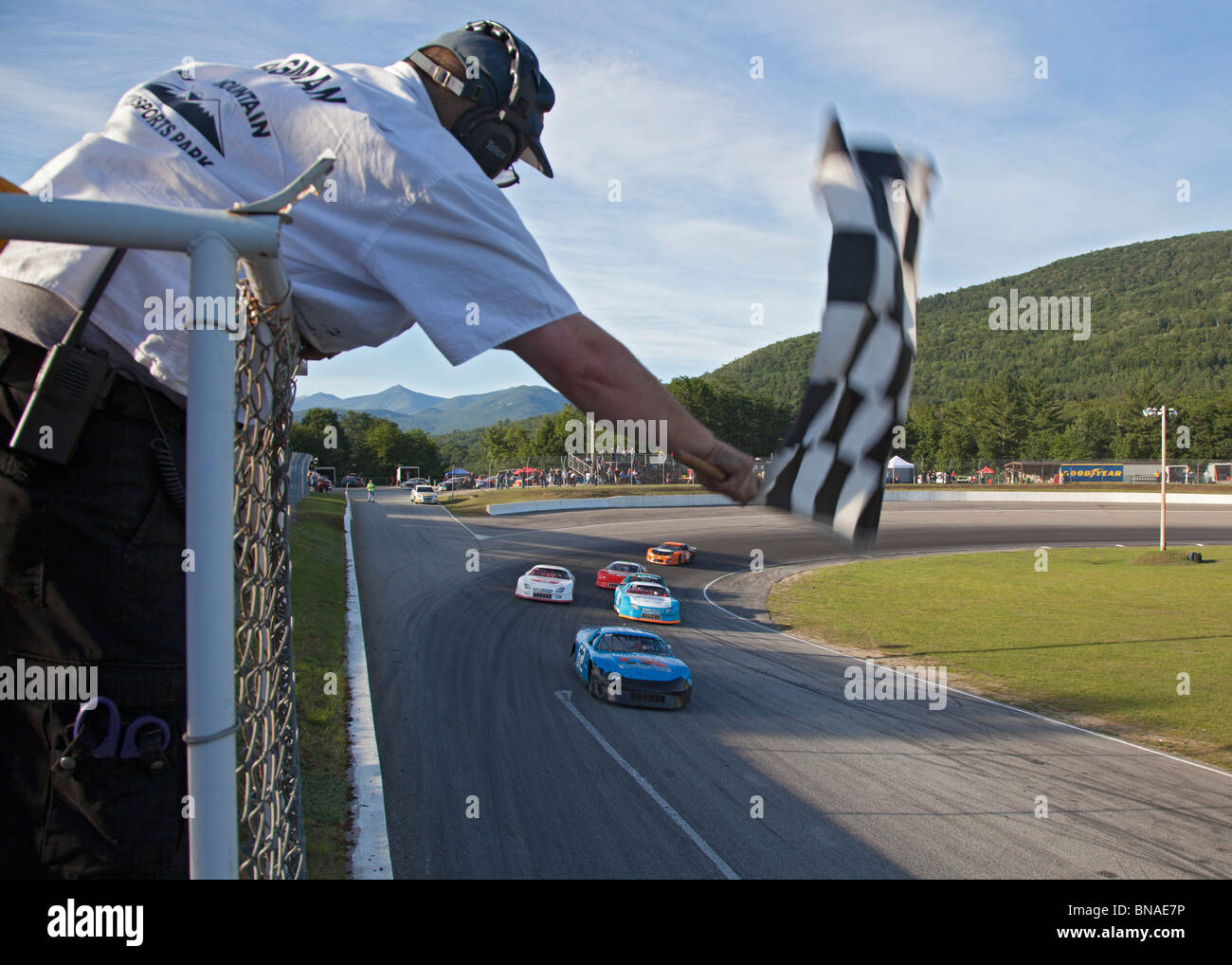 Woodstock, New Hampshire - The flagman waves the checkered flag during stock car racing at White Mountain Motorsports Park. Stock Photo