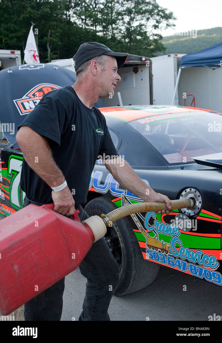 Woodstock, New Hampshire - A mechanic fuels a race car in the pits during stock car racing at White Mountain Motorsports Park. Stock Photo