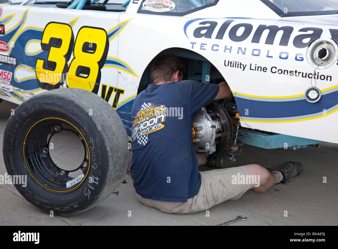 Woodstock, New Hampshire - A mechanic works on a car in the pits during stock car racing at White Mountain Motorsports Park. Stock Photo