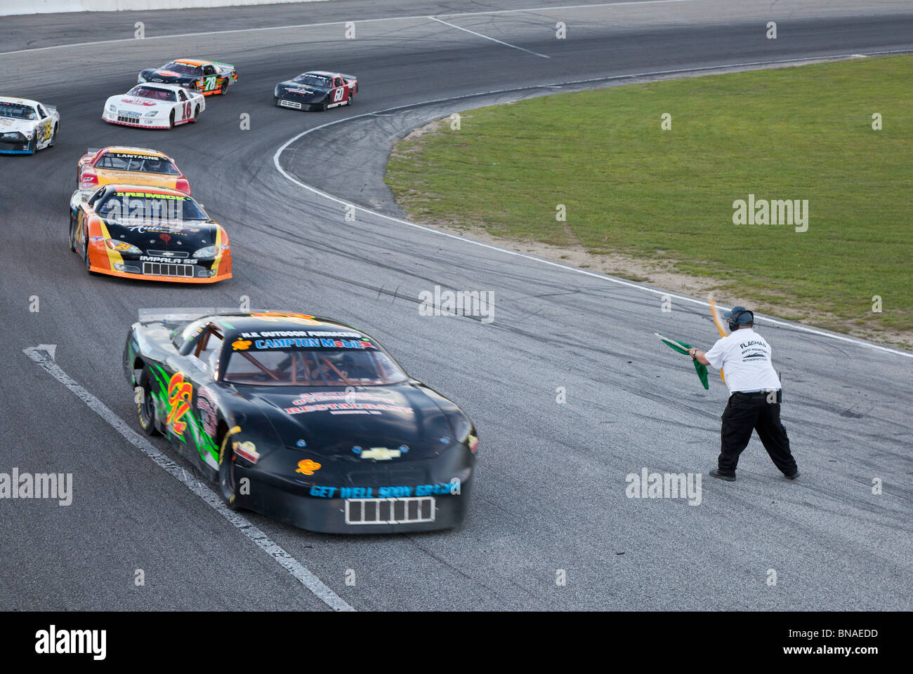 Woodstock, New Hampshire - Stock car racing at White Mountain Motorsports Park. The flagman slows cars after a collision. Stock Photo