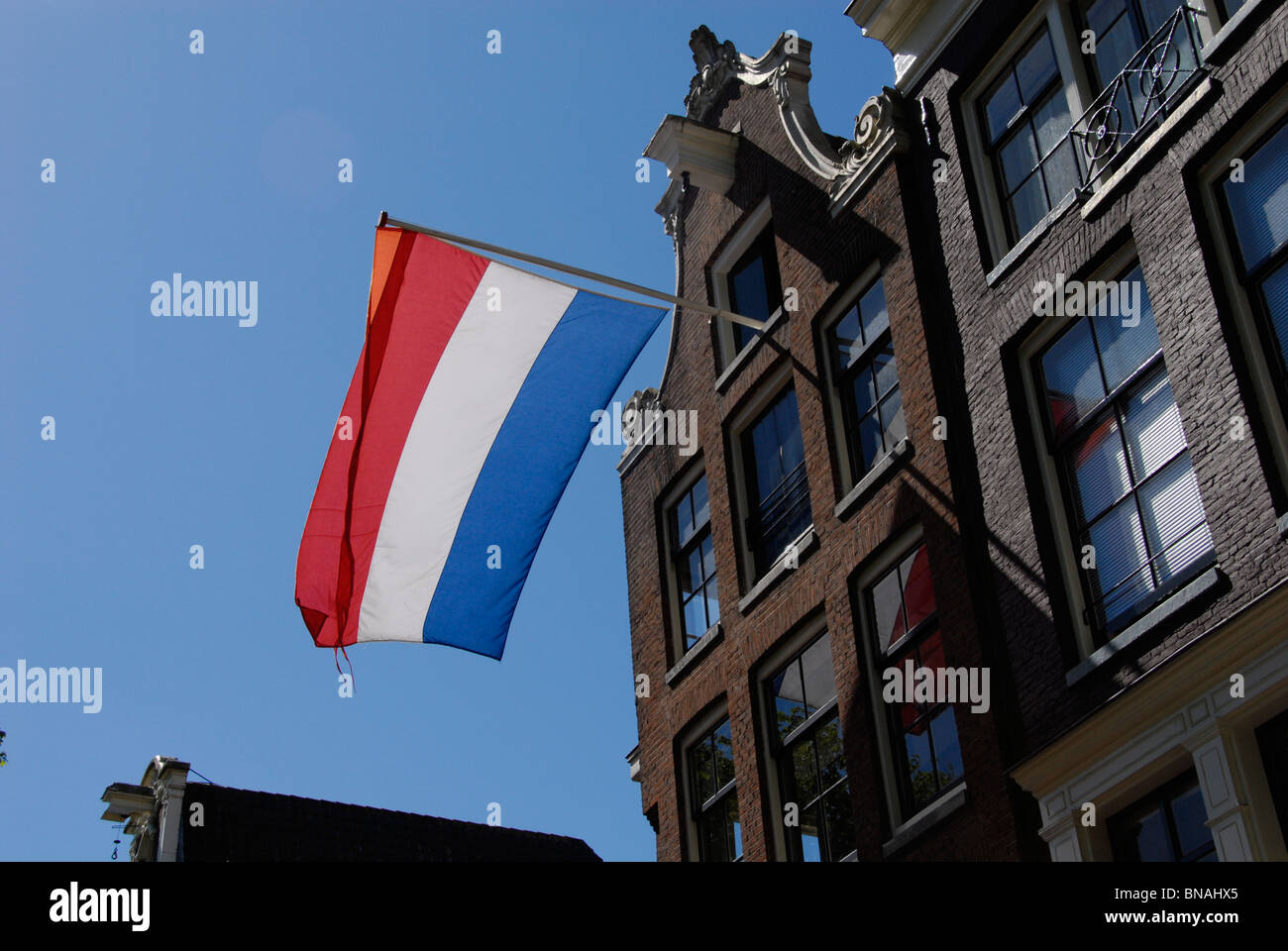 queensday koninginnedag netherlands amsterdam dutch house klokgevel waving wind sunny Stock Photo