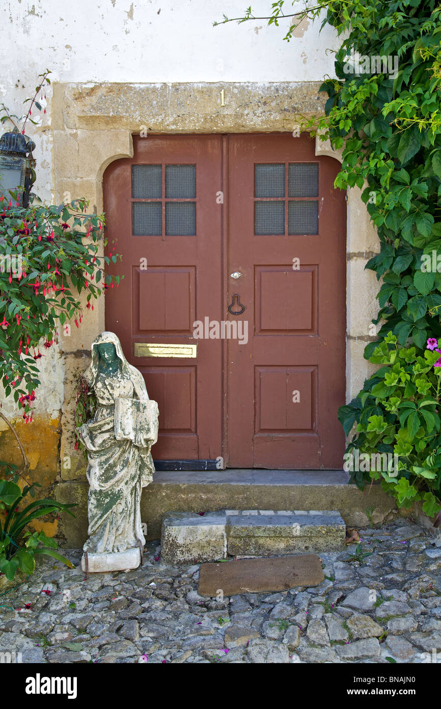 Brown Wood Door of the Medieval Town of Obidos surrounded by a Green Vine Stock Photo