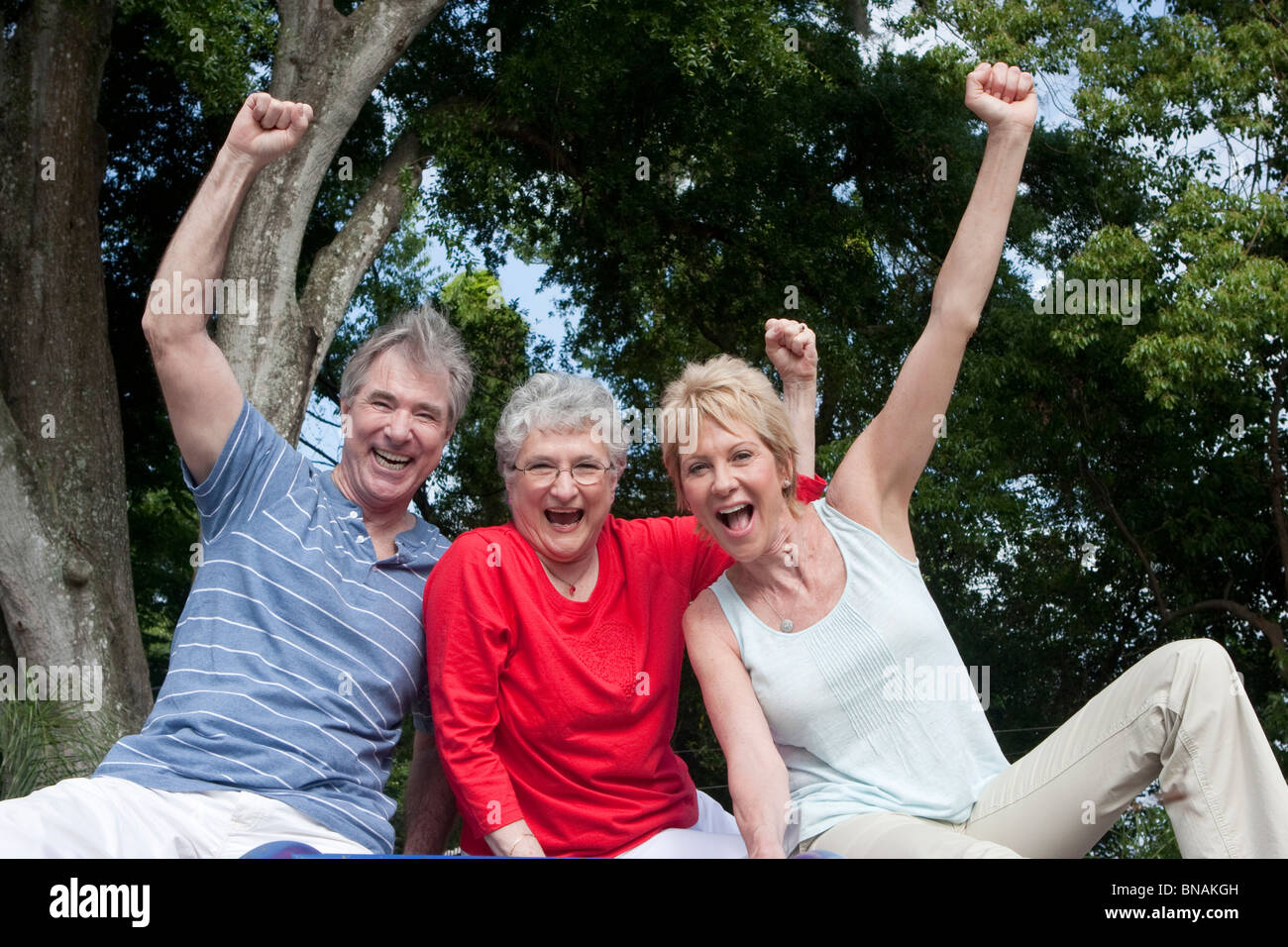 Three seniors sitting on top of playground equipment celebrating Stock
