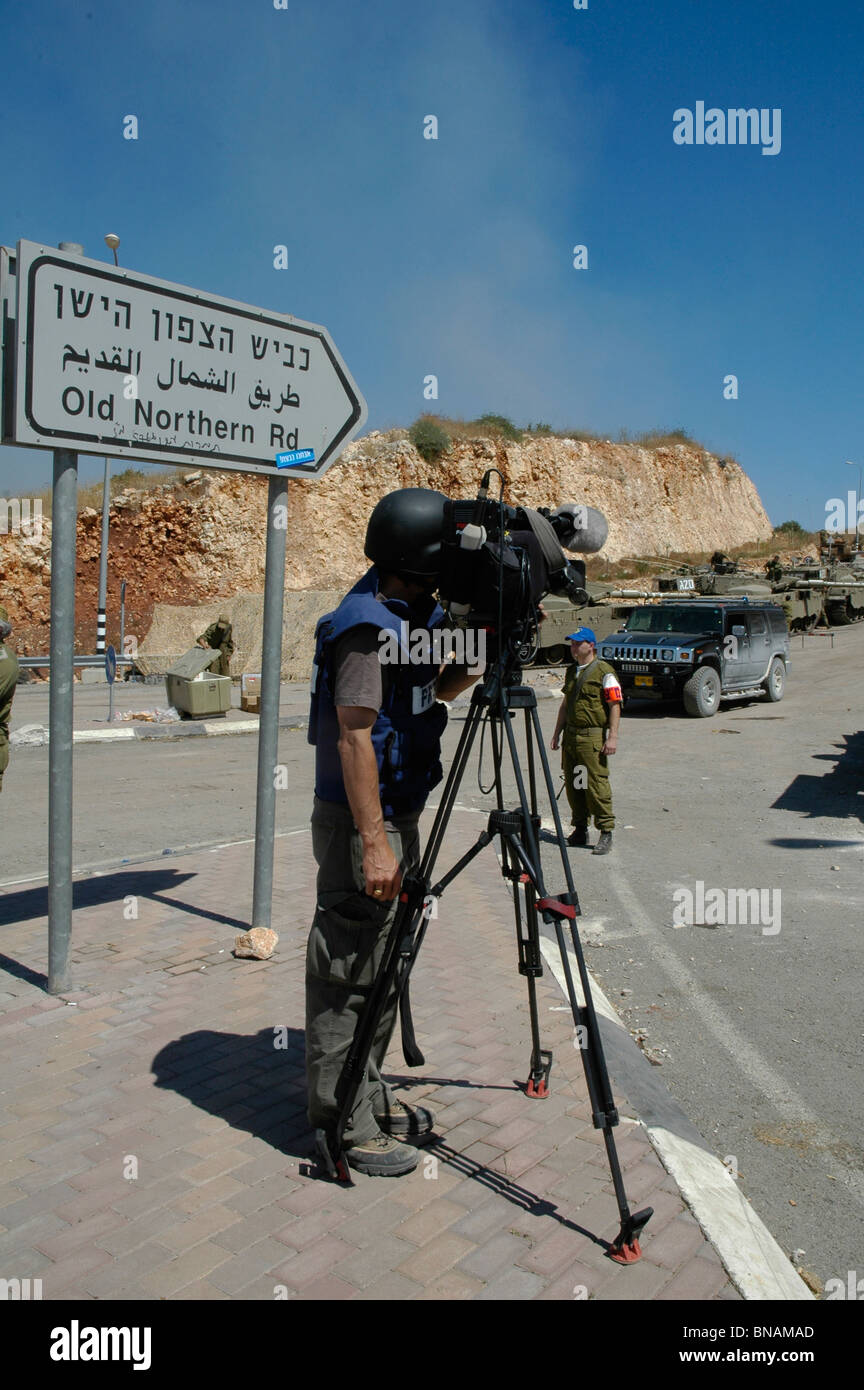 TV news crew wearing protective flak jacket filming Israeli troops mass
