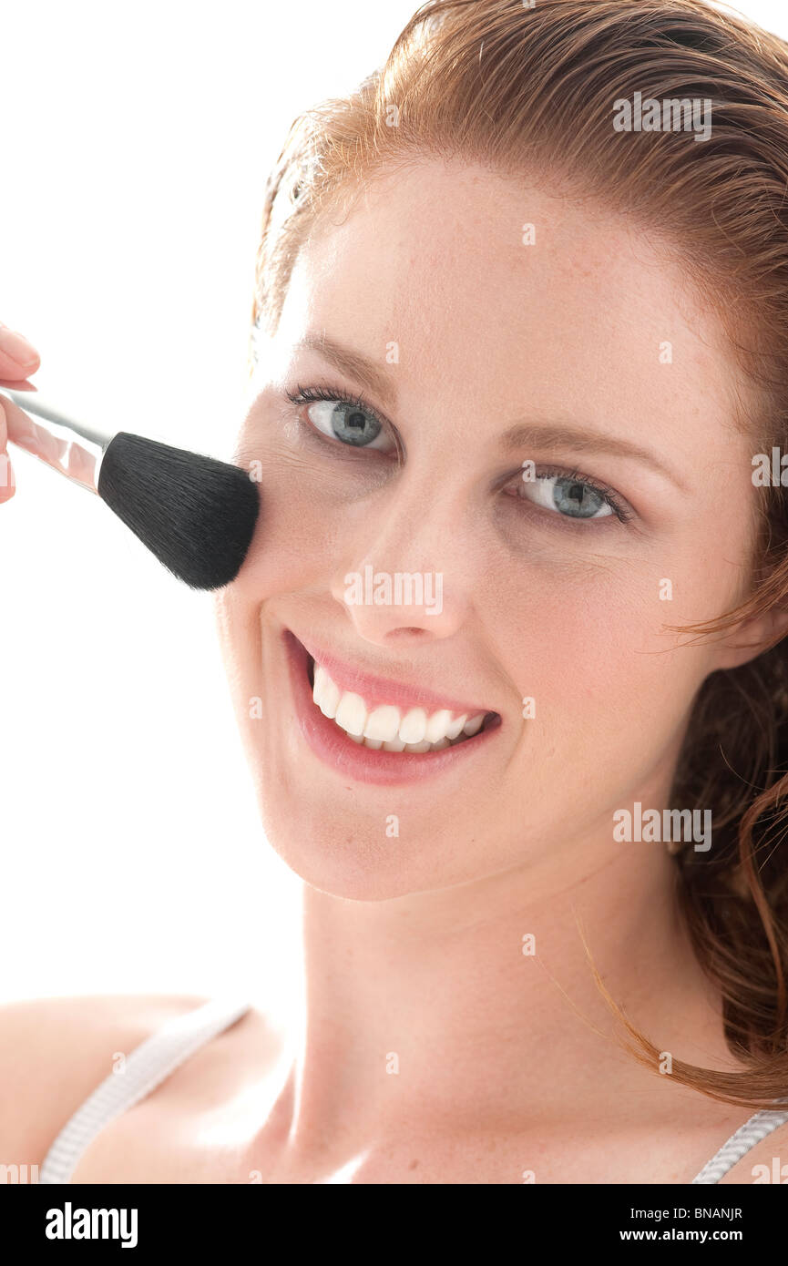 young woman applies blush on cheeks Stock Photo