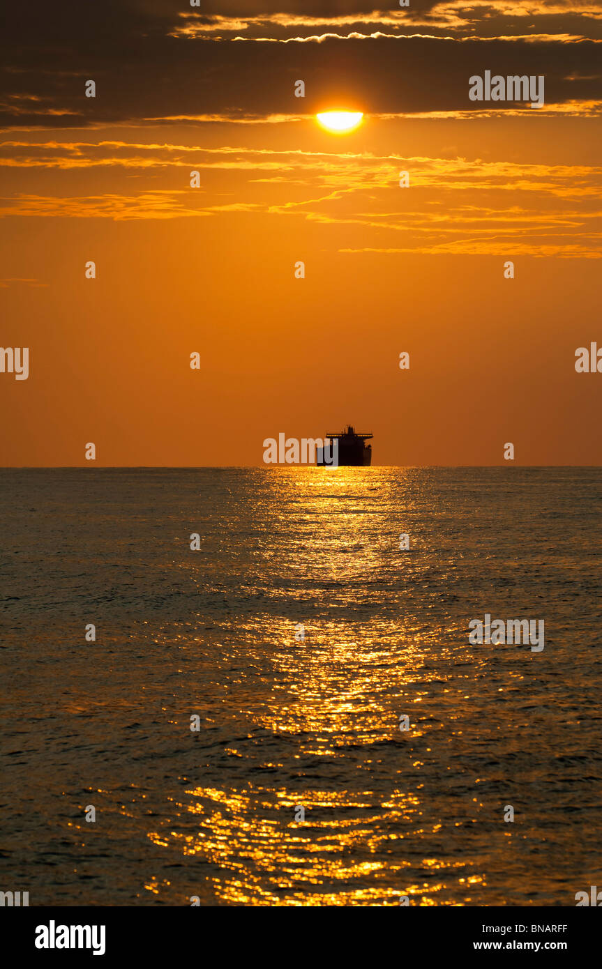 A cargo ship at sunset on the Mediterranean Sea near Formentera Island, Balearic Islands, Spain Stock Photo
