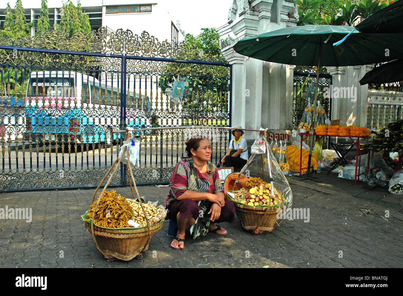 Seated Woman selling fruit from two baskets Bangkok Thailand Stock Photo