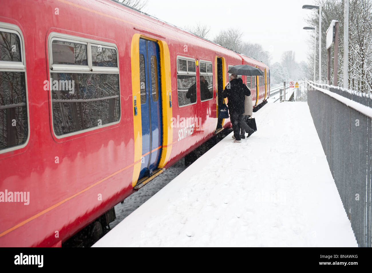 Two people boarding a  South West train  at station on a snowy day Stock Photo