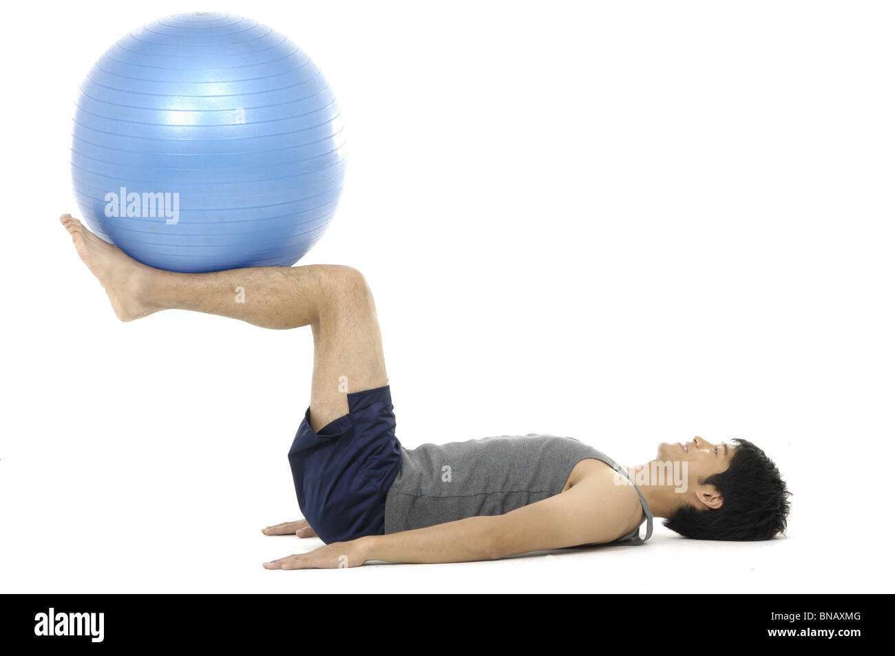 Side profile of a young man exercising with a fitness ball Stock Photo