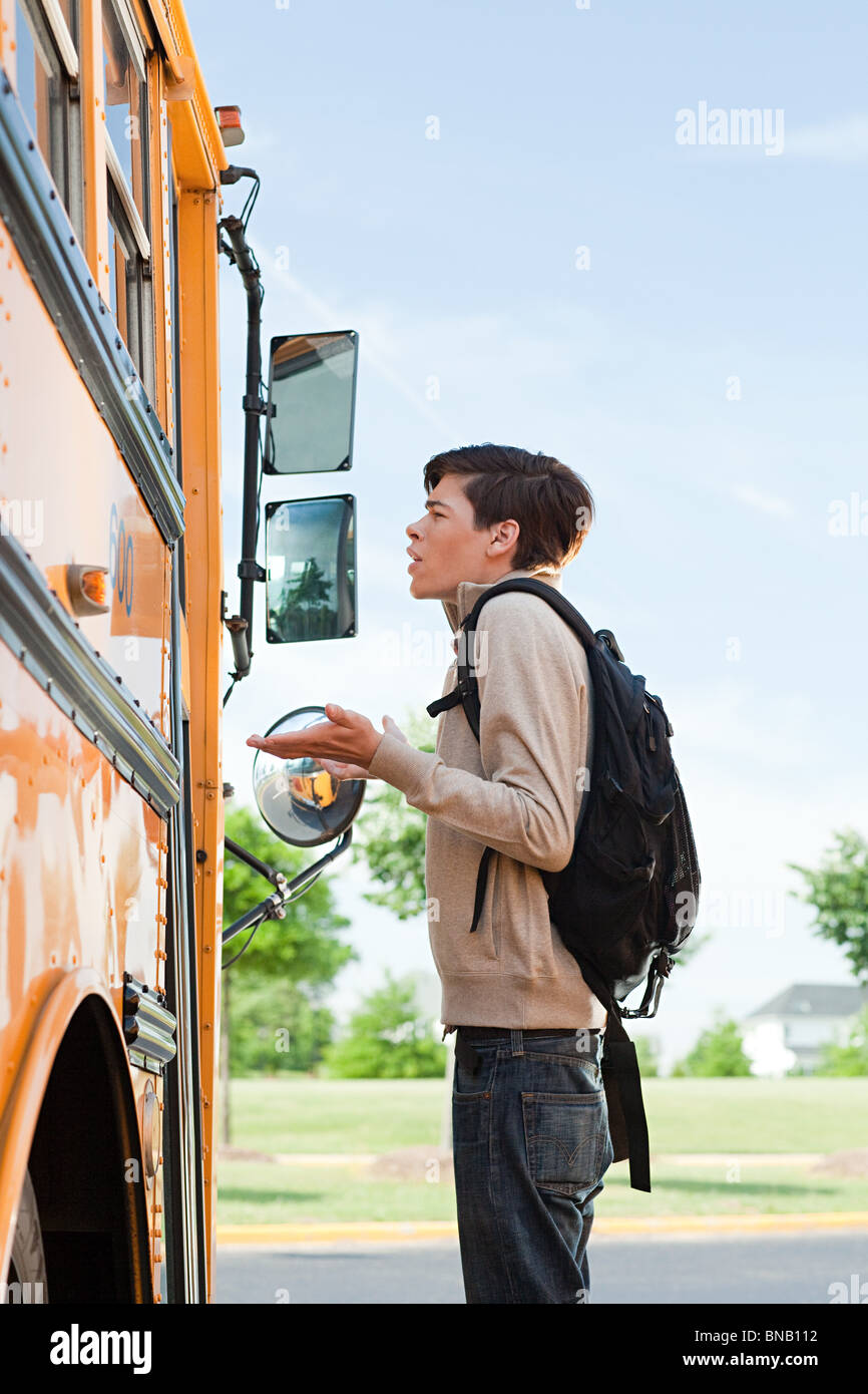 Male high school student standing outside school bus door Stock Photo
