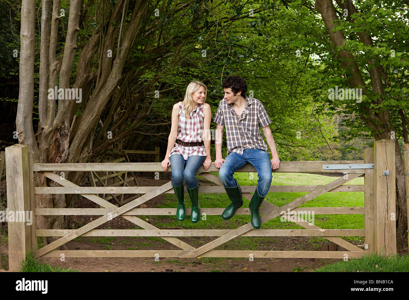 Young couple sitting on gate Stock Photo