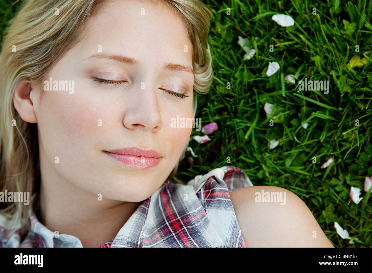Young woman lying on grass with eyes closed Stock Photo Alamy