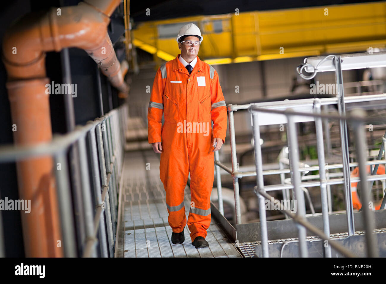 Engineer walking along walkway in factory Stock Photo