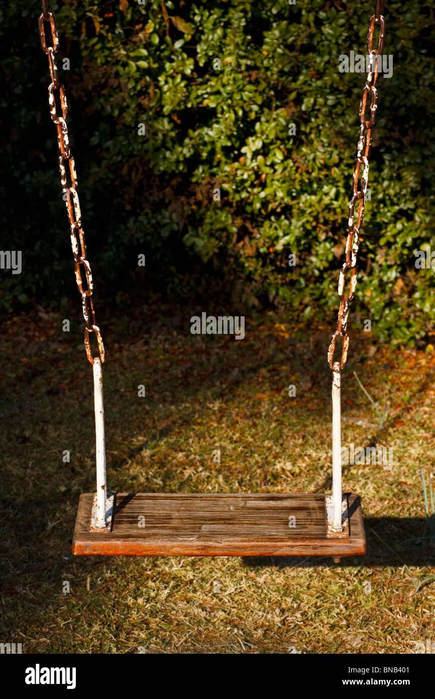 Playground swing in the first rays of early morning sunlight. Stock Photo