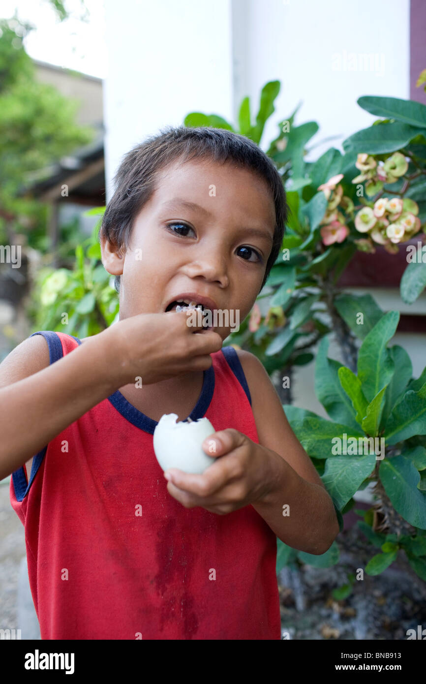 A Filipino child enjoys a balut, or cooked fertilized duck egg, in Oriental Mindoro, Philippines. Stock Photo