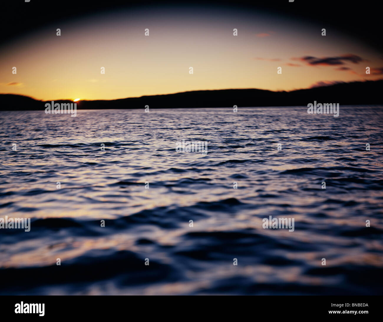 Select focus image of sun behind some trees on a lake Stock Photo