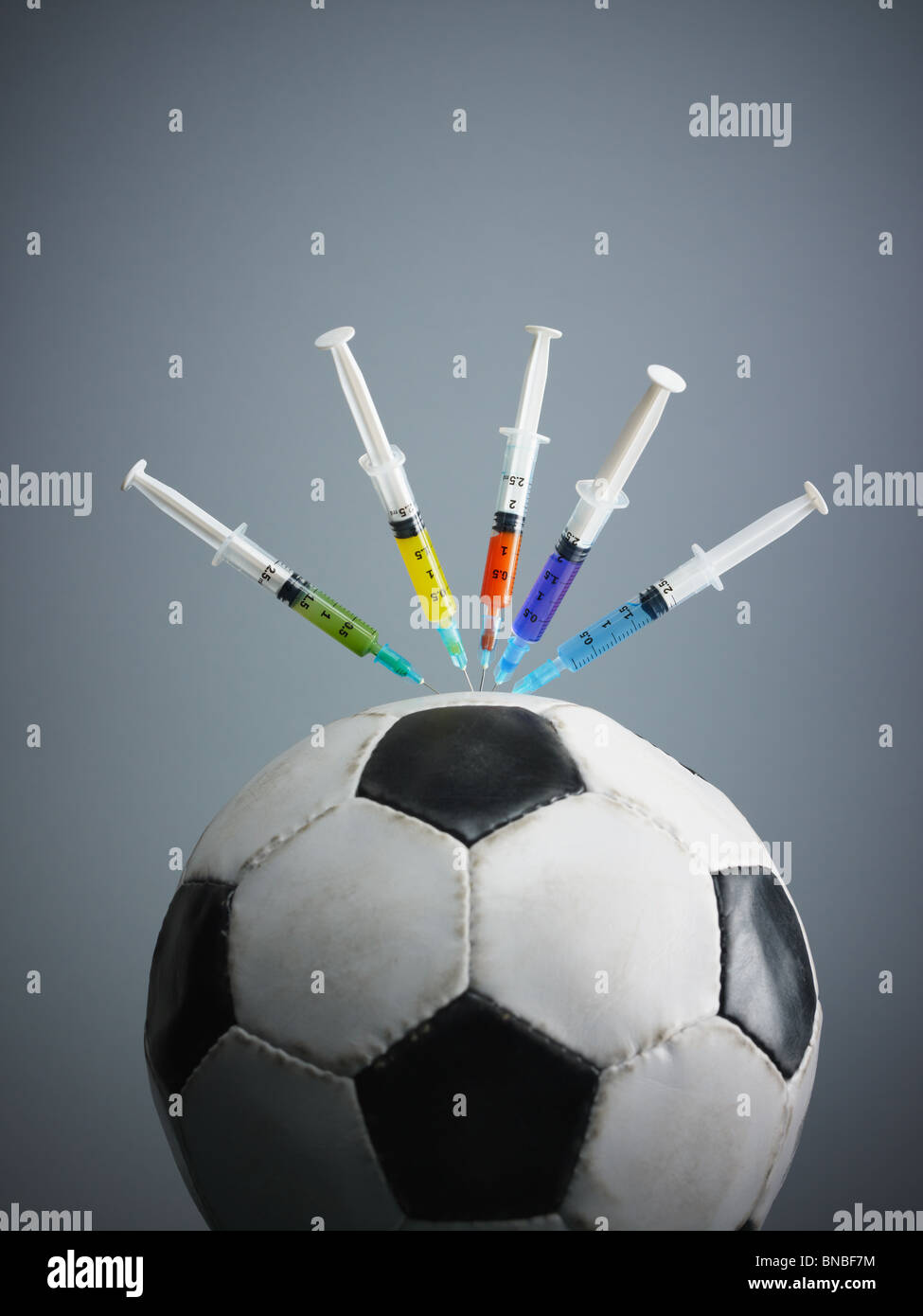 five syringes threaded in soccer ball. Copy space Stock Photo