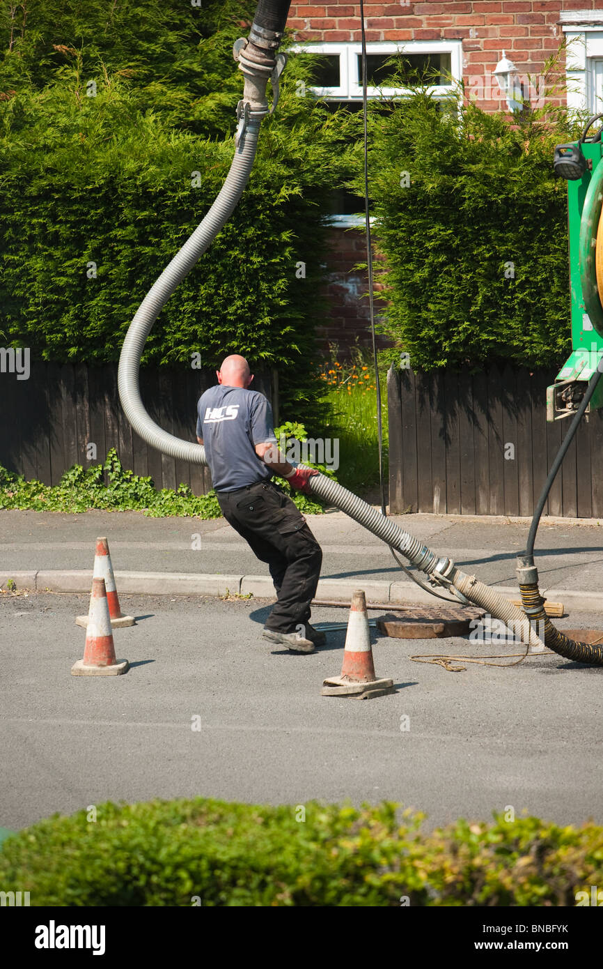 Drain Workers clearing drain blockage on housing estate street Stock