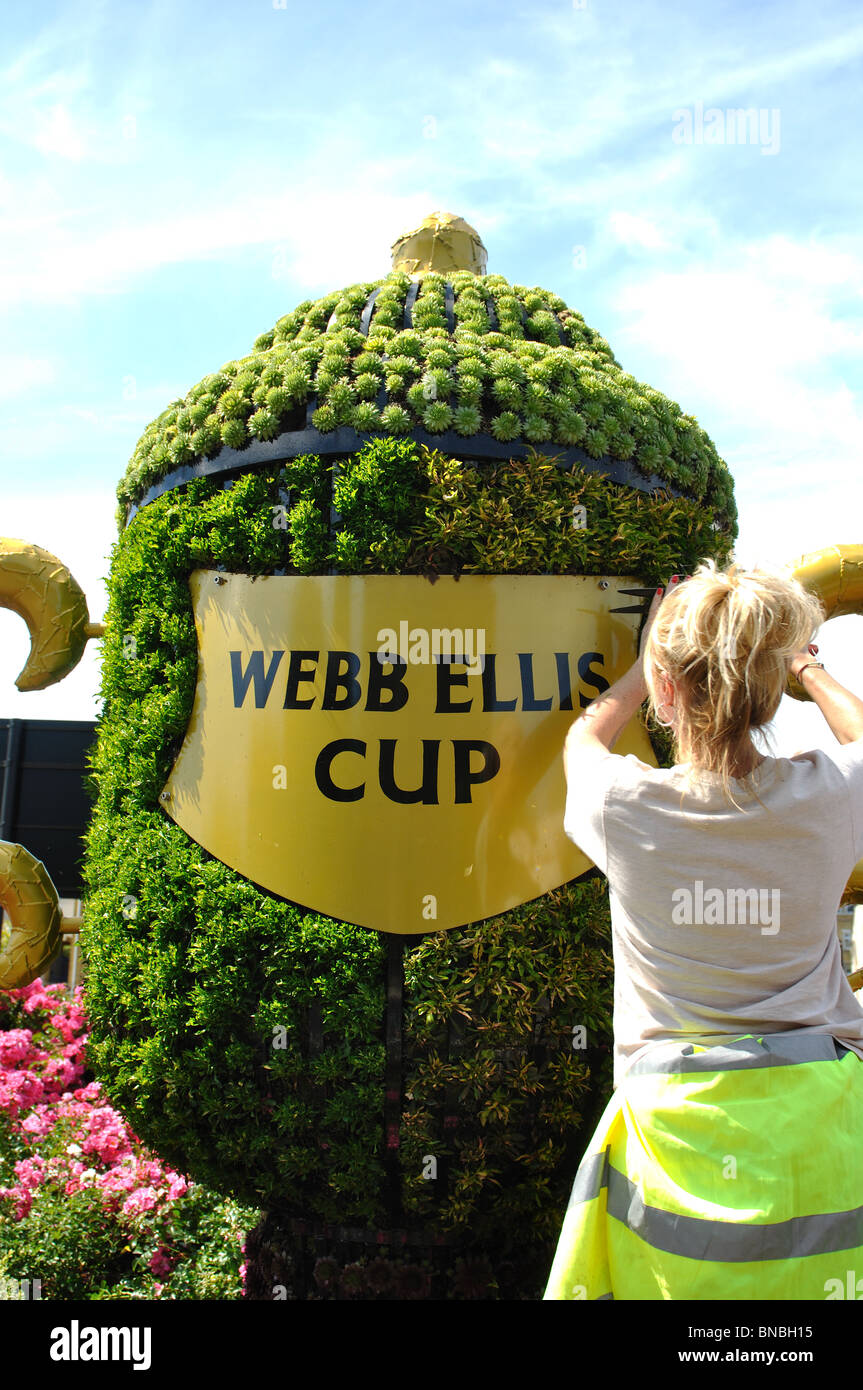 Woman gardener trimming plants on Webb Ellis Cup floral decoration, Rugby, Warwickshire, England, UK Stock Photo