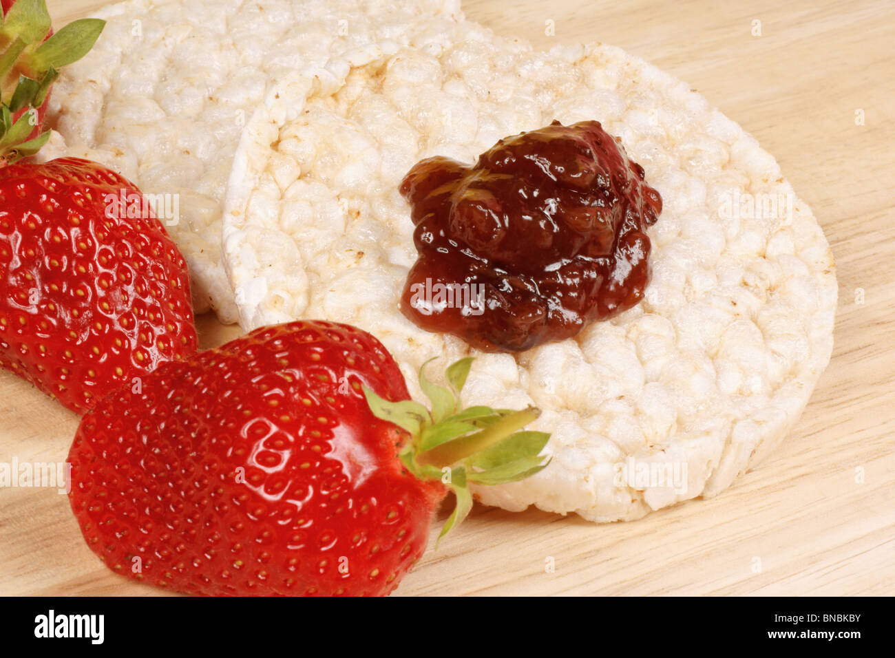 Close-up of two rice cakes with jam and some fresh strawberries on a ...